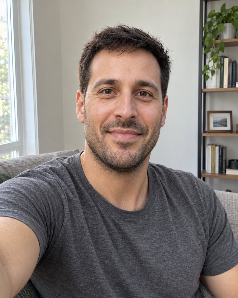 Plain phone selfie of the same man at home by a window