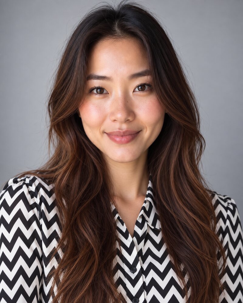 Woman in a blouse with a tight black and white zigzag print that dominates the photo, light grey background